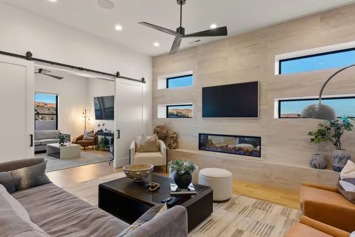 Living area with a barn door, ceiling fan, light wood finished floors, a high end fireplace, and recessed lighting