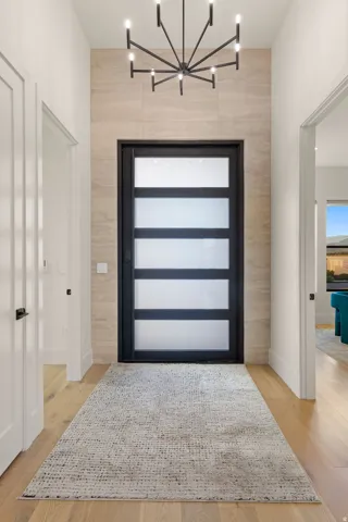 Entryway featuring light wood-style flooring, an accent wall, and a chandelier