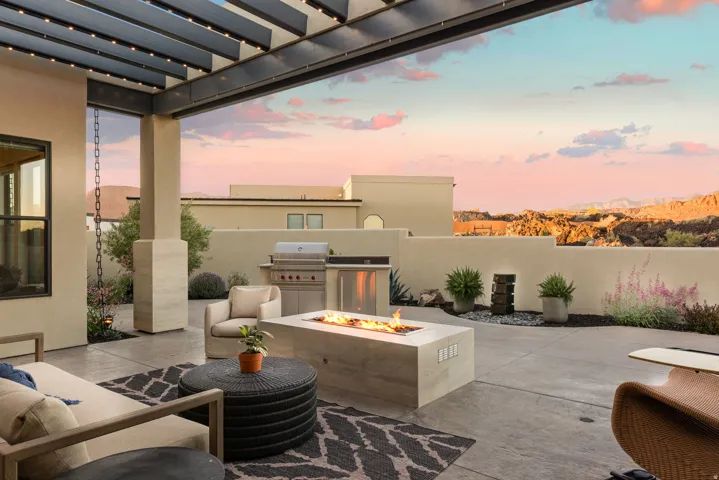Patio terrace at dusk with an outdoor fire pit, a patio area, exterior kitchen, and a pergola