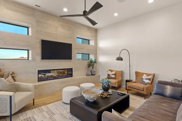 Living room with wood finished floors, a high end fireplace, recessed lighting, and ceiling fan