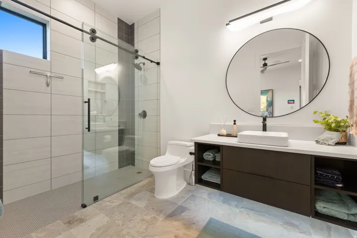 Bathroom featuring vanity, a stall shower, and light stone finish flooring