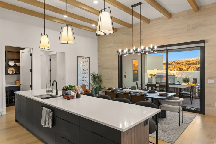 Kitchen featuring modern cabinets, a large island, dark cabinets, a kitchen breakfast bar, and light stone countertops