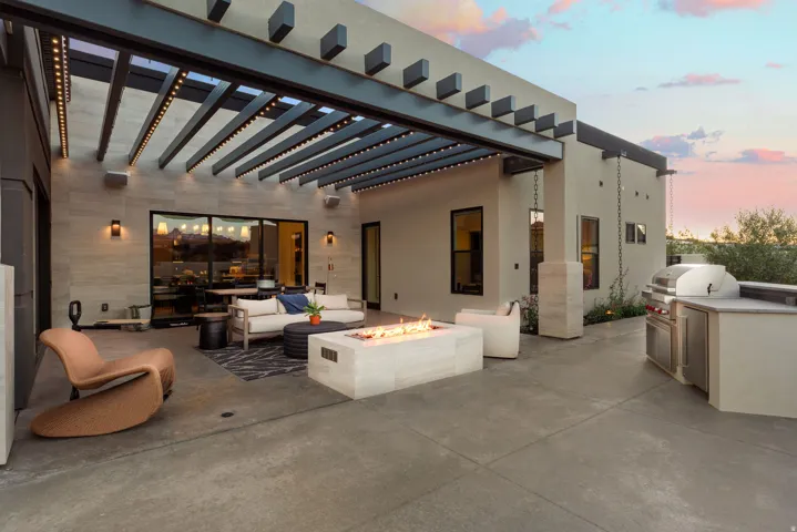 Patio terrace at dusk featuring an outdoor kitchen and area to lounge, an outdoor fire pit, a patio, and a pergola