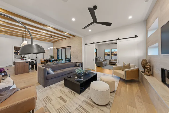 Living area with a barn door, ceiling fan, light wood-type flooring, recessed lighting, and a fireplace