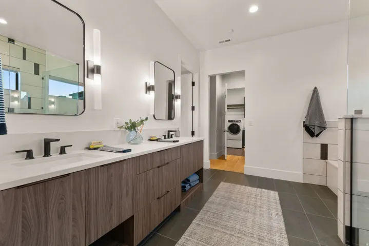 Full bath featuring double vanity, a tile shower, recessed lighting, washer / dryer, and a spacious closet