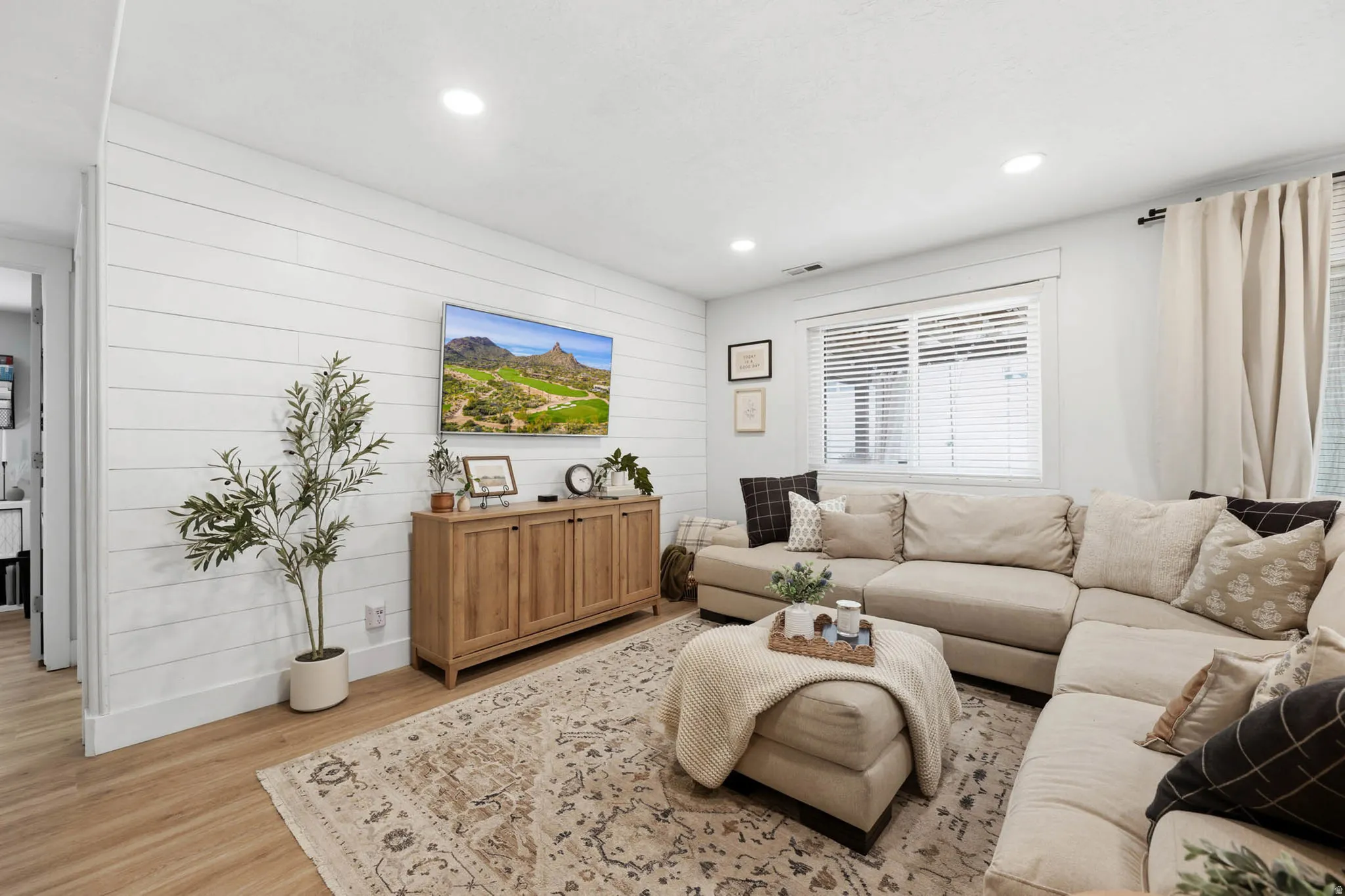 Living room with light wood finished floors, recessed lighting, and wooden walls