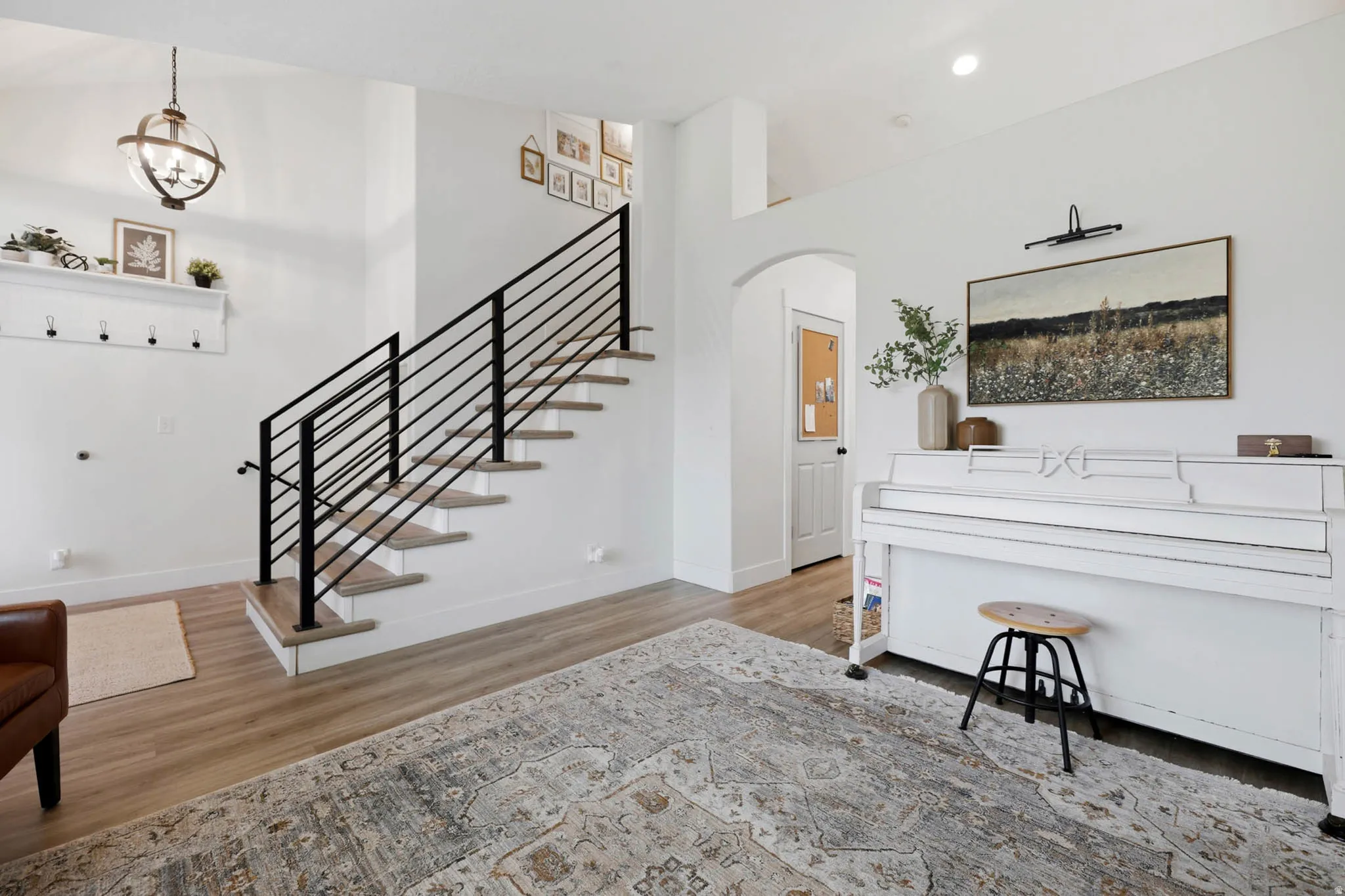 Entryway with arched walkways, light wood-type flooring, a high ceiling, and recessed lighting