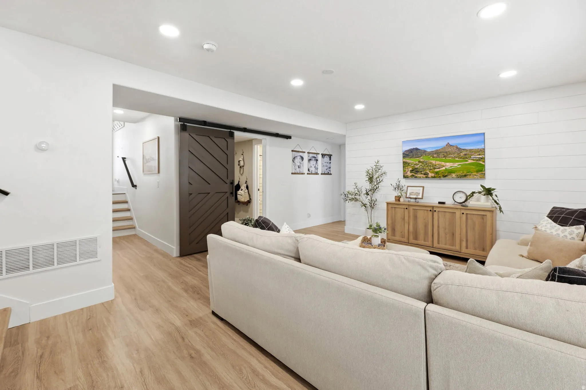 Living room featuring a barn door, light wood-type flooring, and recessed lighting