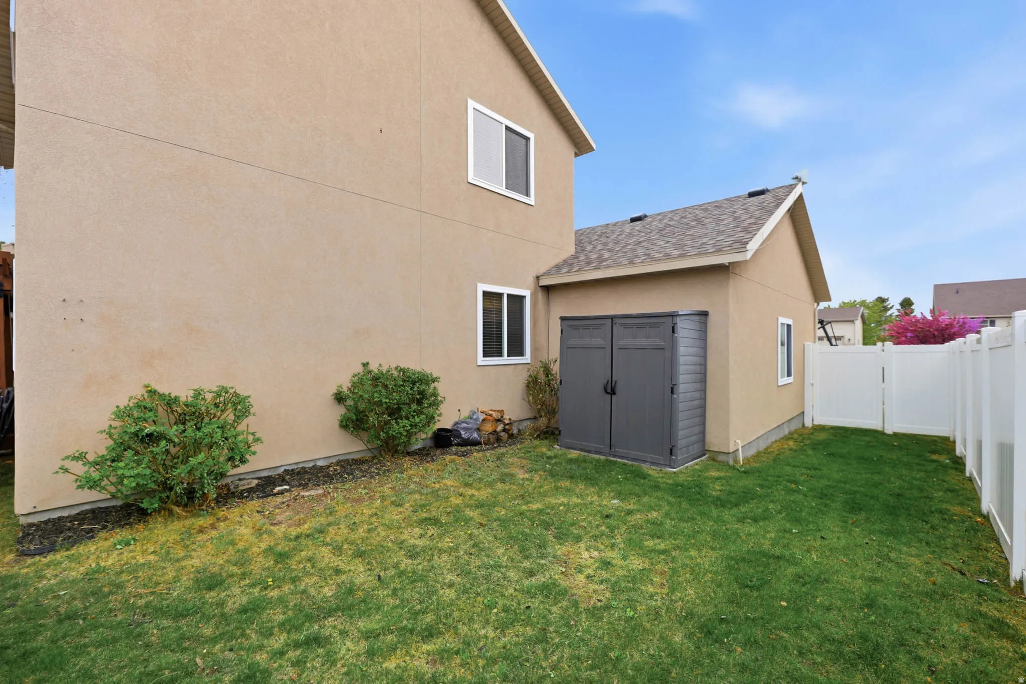 Back of house with a fenced backyard, stucco siding, a storage shed, and a shingled roof