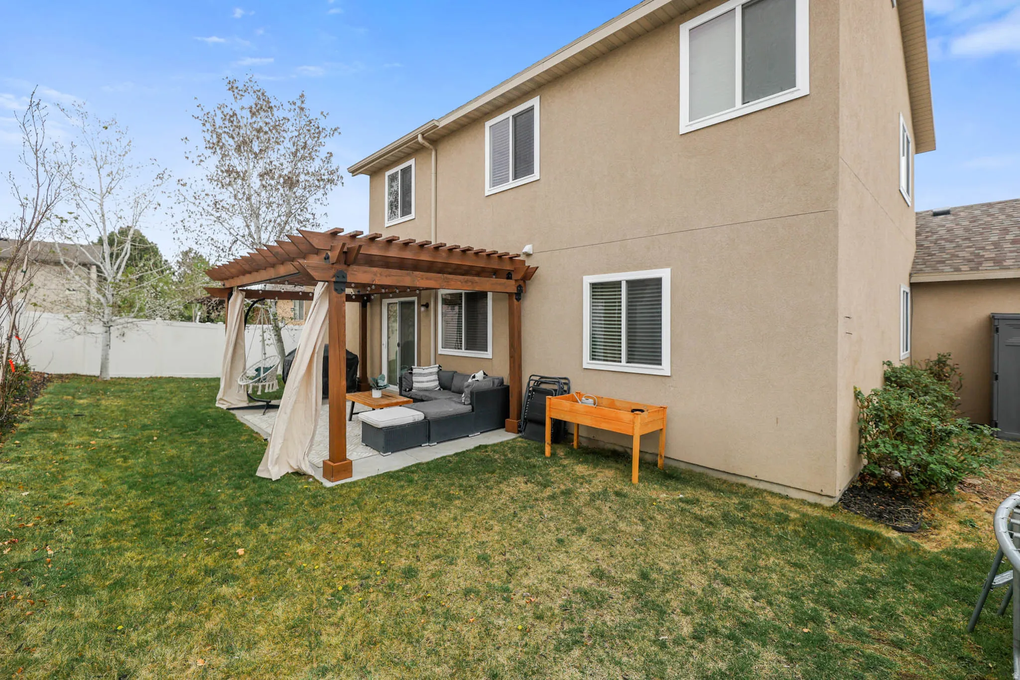 Rear view of house with outdoor lounge area, a pergola, stucco siding, and a fenced backyard