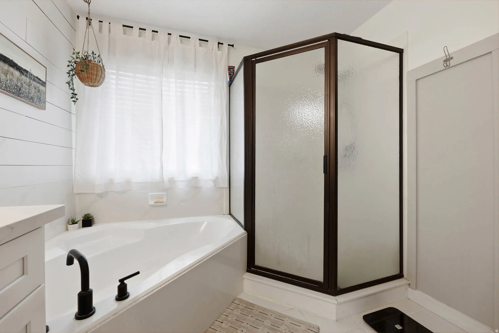 Full bath featuring vanity, a stall shower, a garden tub, and light tile patterned floors