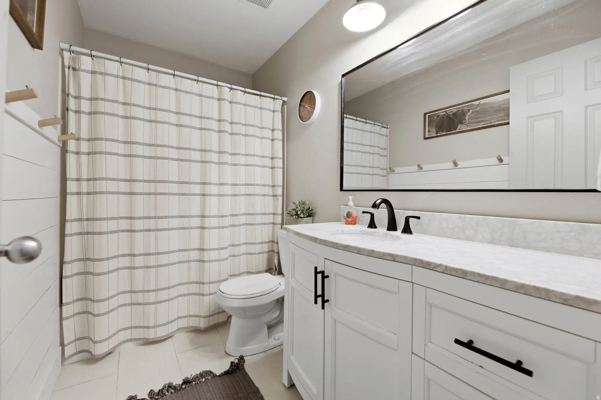 Full bathroom featuring vanity, a shower with shower curtain, and light tile patterned flooring
