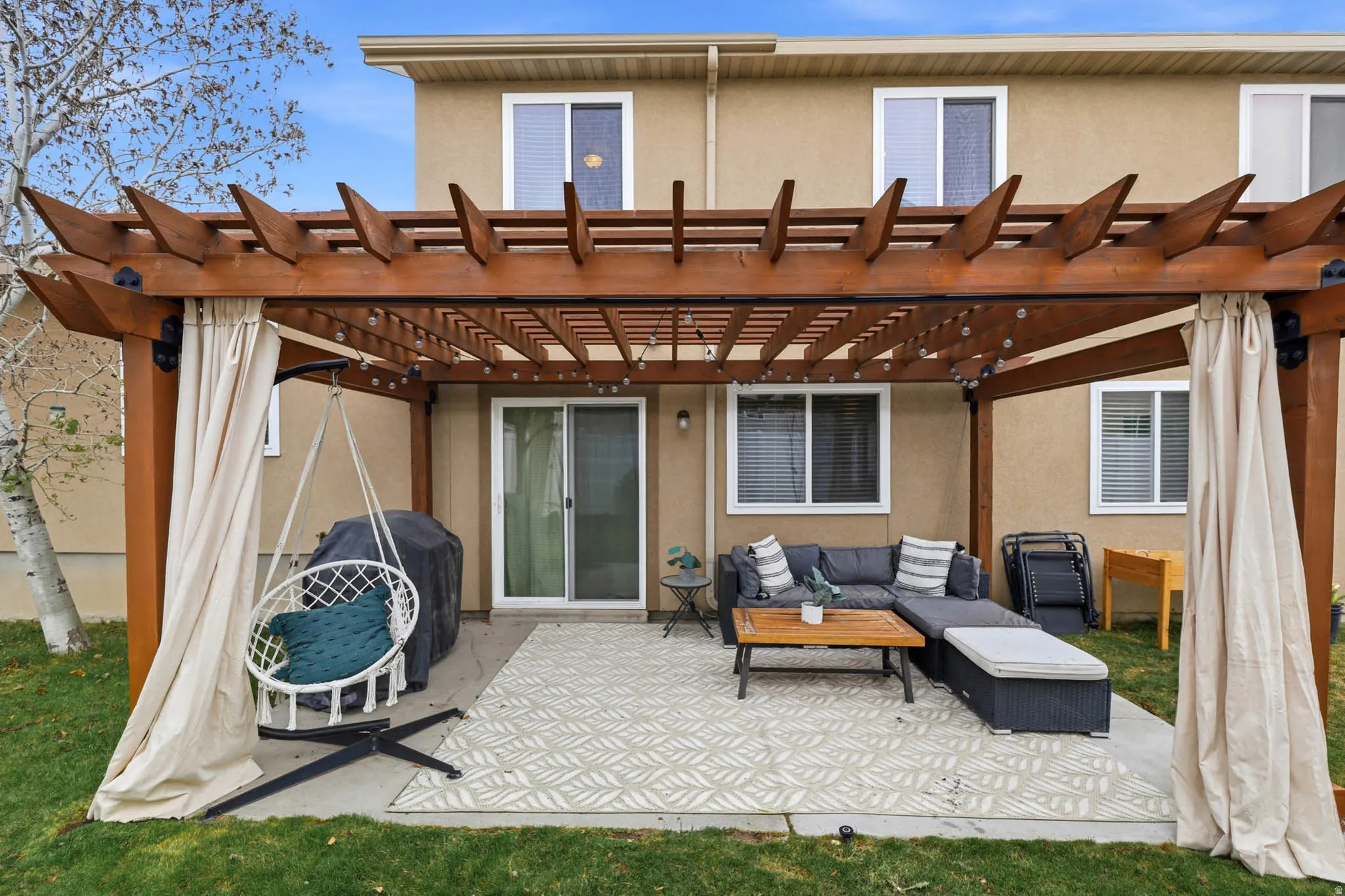 Back of house with stucco siding, a patio, an outdoor lounge area, and a pergola