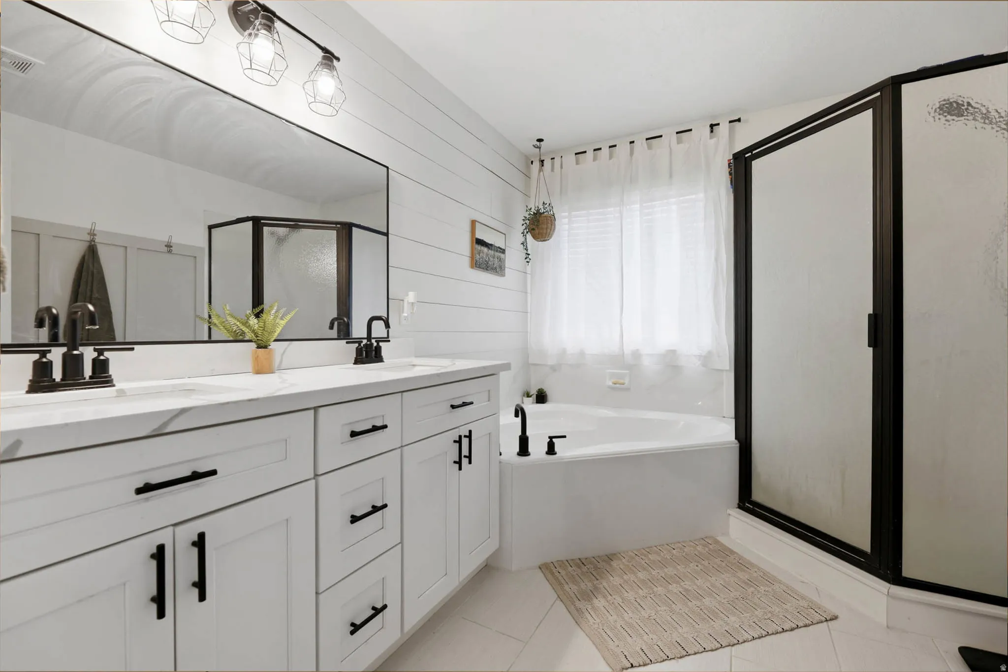Full bathroom with double vanity, a stall shower, light tile patterned flooring, a garden tub, and wooden walls