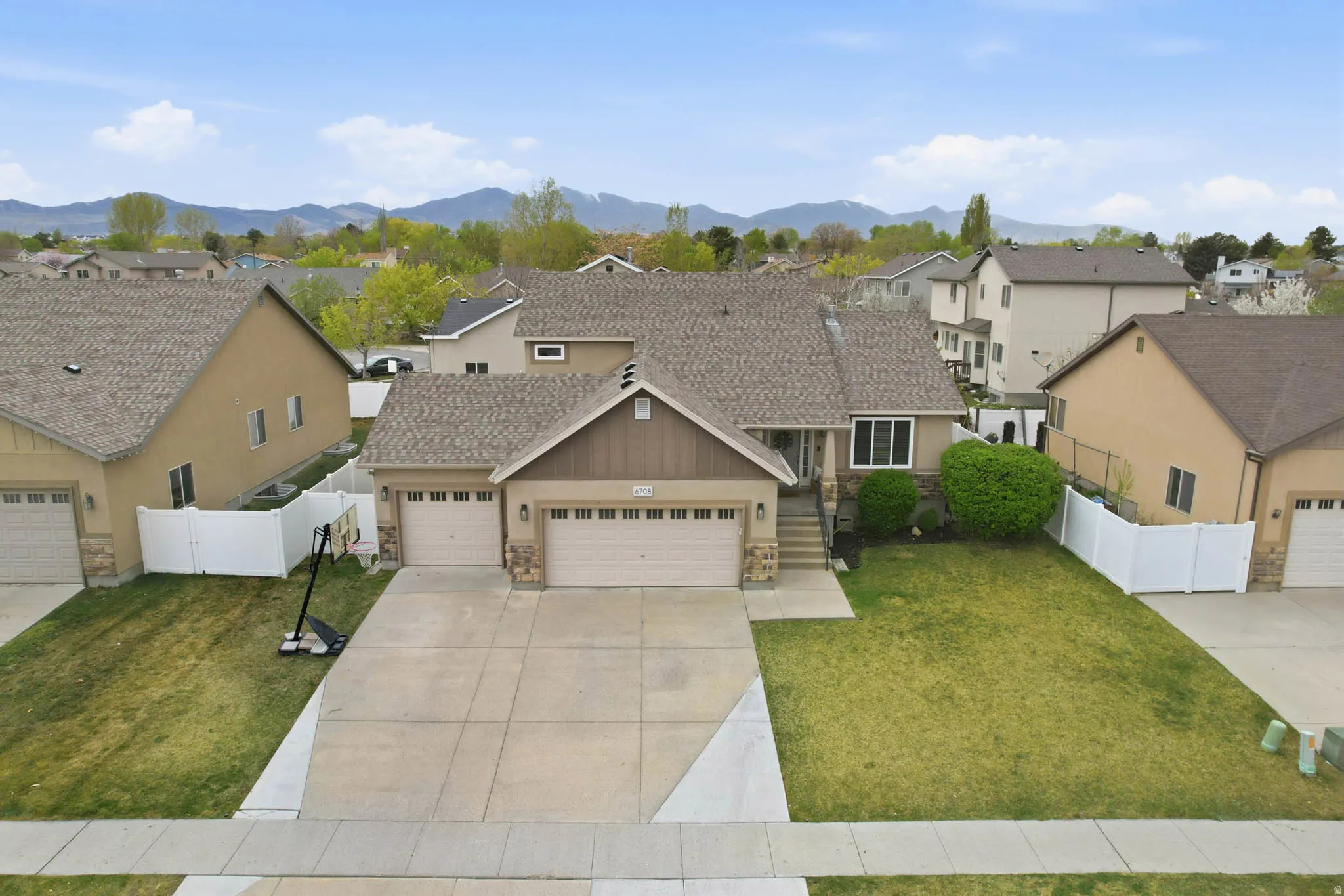 View of front facade featuring stone siding, a residential view, a garage, driveway, and a mountain view