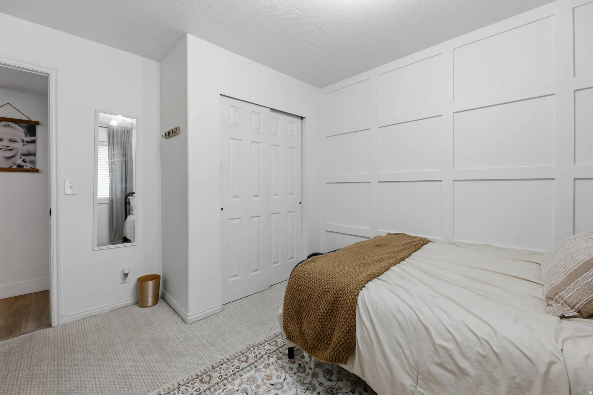 Bedroom featuring carpet, a closet, a decorative wall, and a textured ceiling