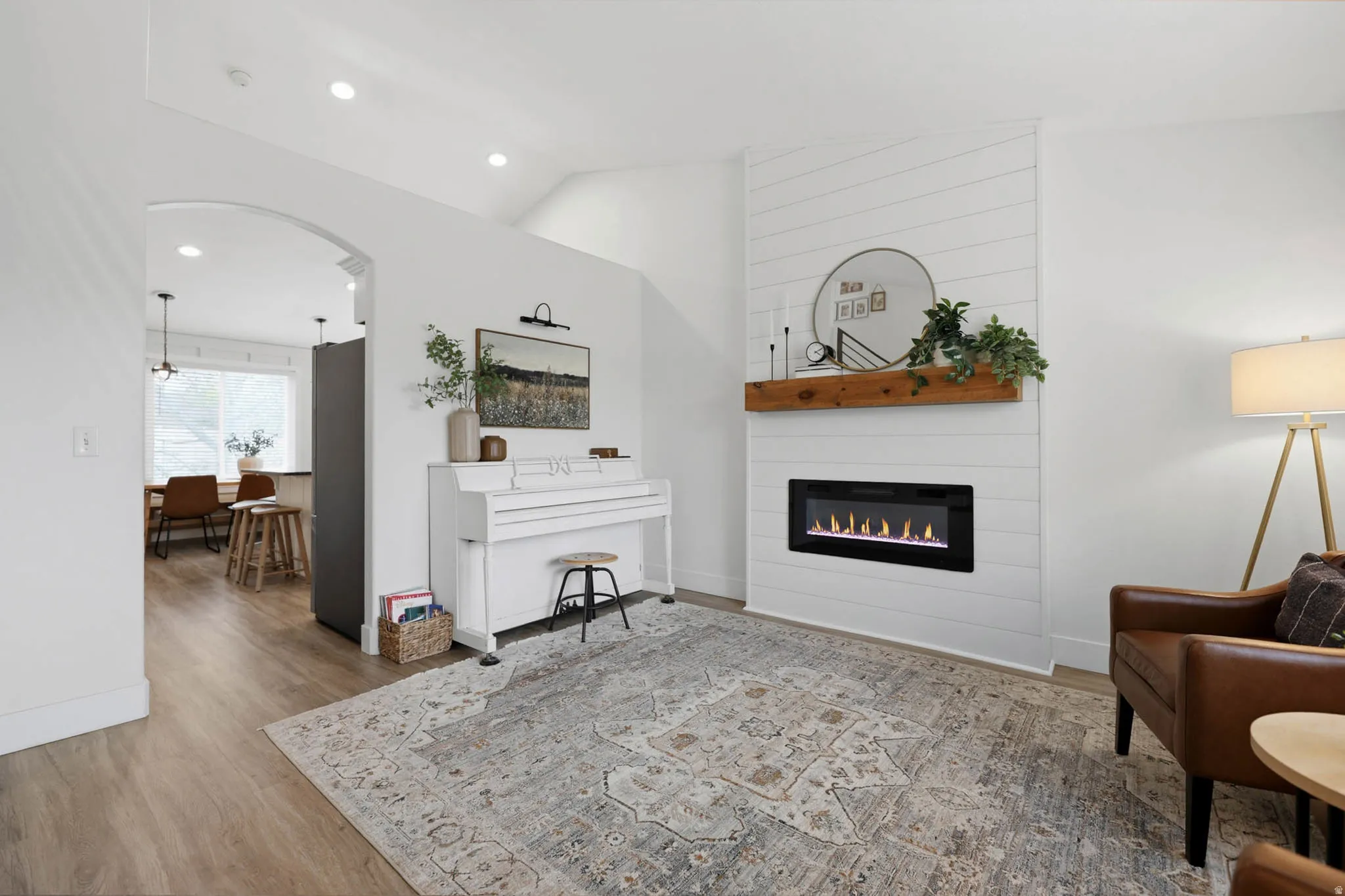 Living room featuring arched walkways, vaulted ceiling, wood finished floors, recessed lighting, and a fireplace