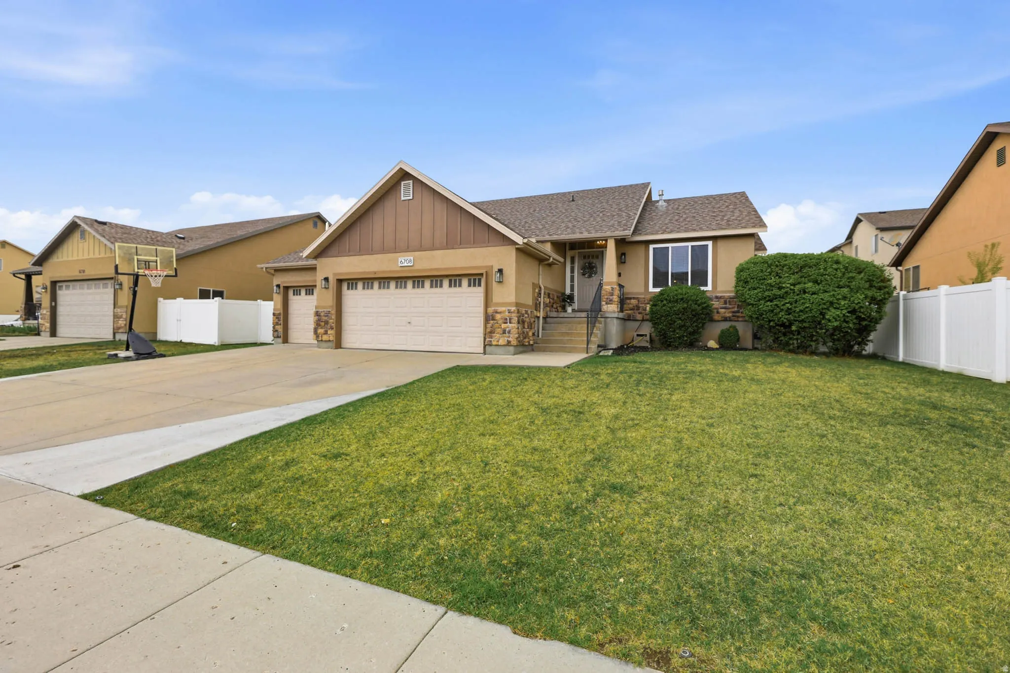 View of front of property featuring an attached garage, driveway, stone siding, a porch, and roof with shingles