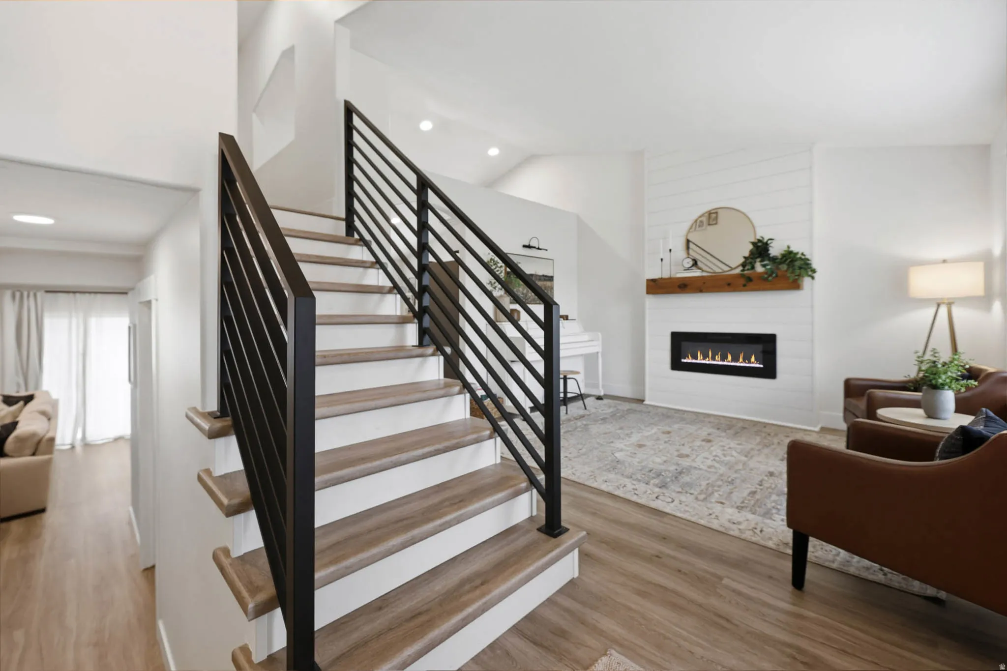 Staircase featuring wood finished floors, a large fireplace, recessed lighting, and a high ceiling