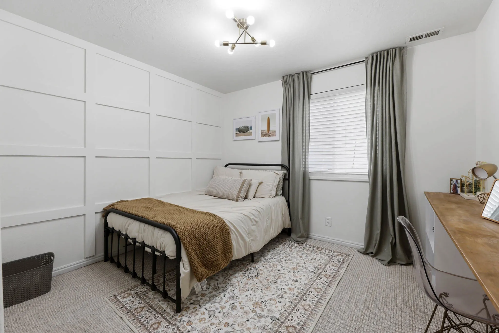 Bedroom featuring light carpet, a decorative wall, and hanging lights