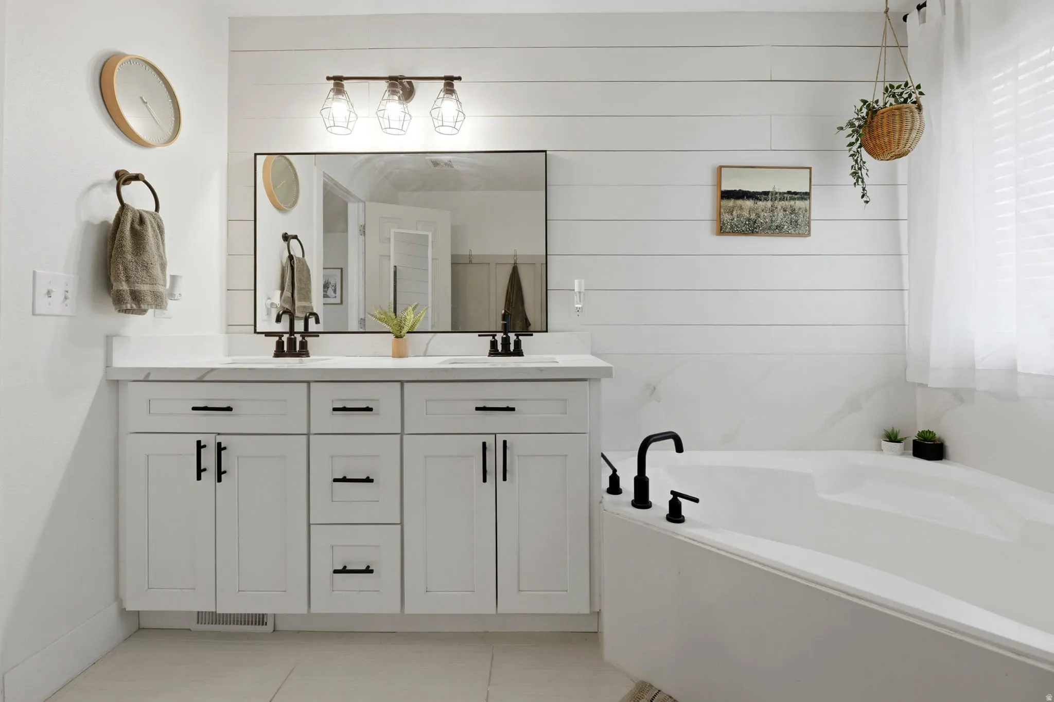 Full bath with double vanity, a bath, light tile patterned flooring, and wood walls