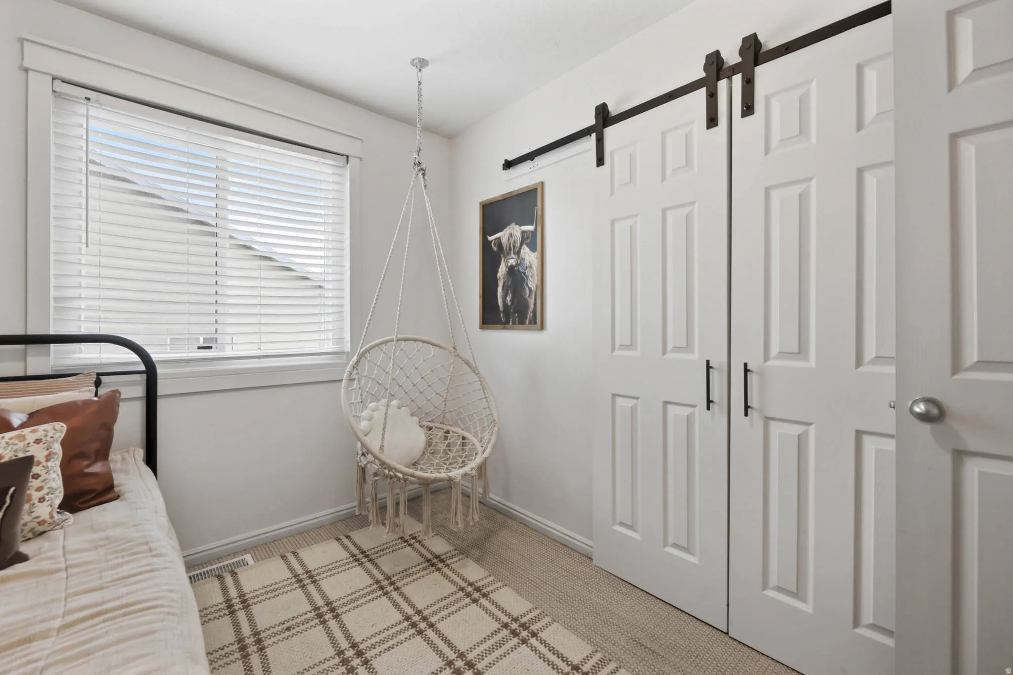 Bedroom with a barn door and light colored carpet