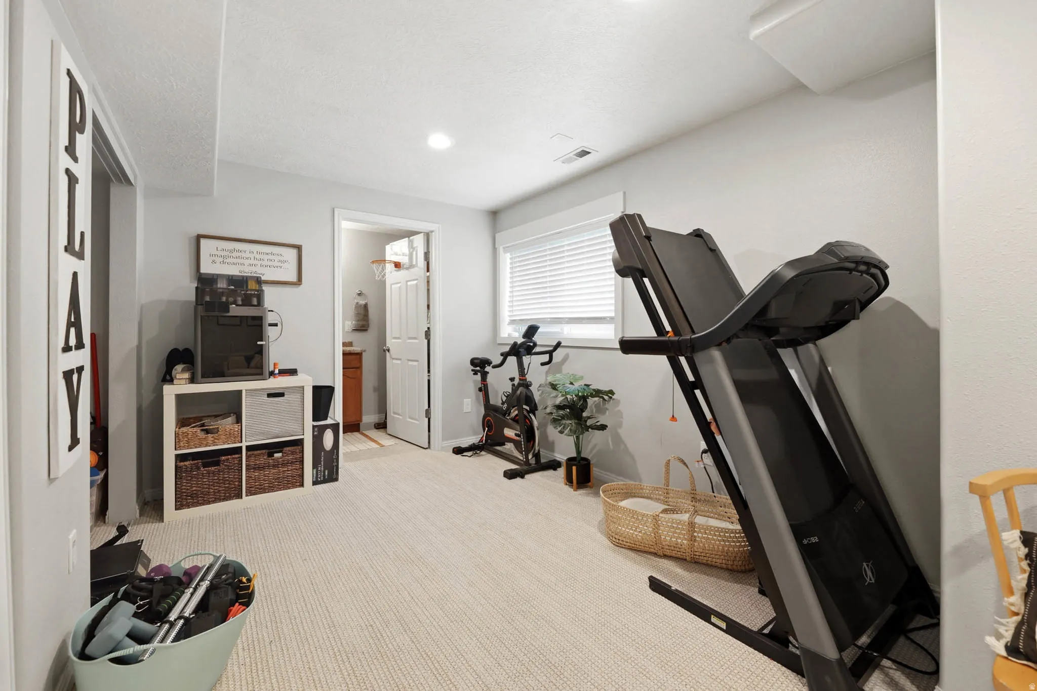 Exercise room featuring light colored carpet and baseboards