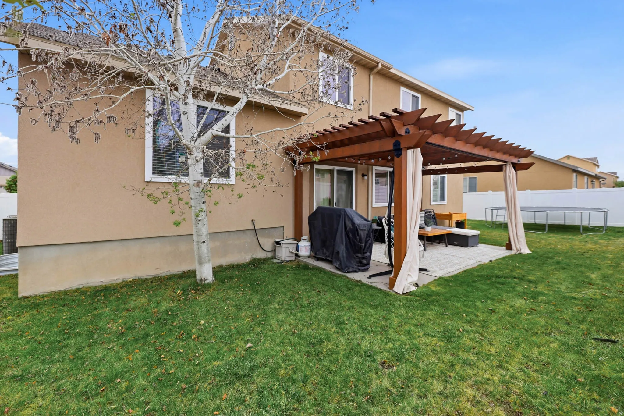 Rear view of property featuring stucco siding, a patio area, and a pergola