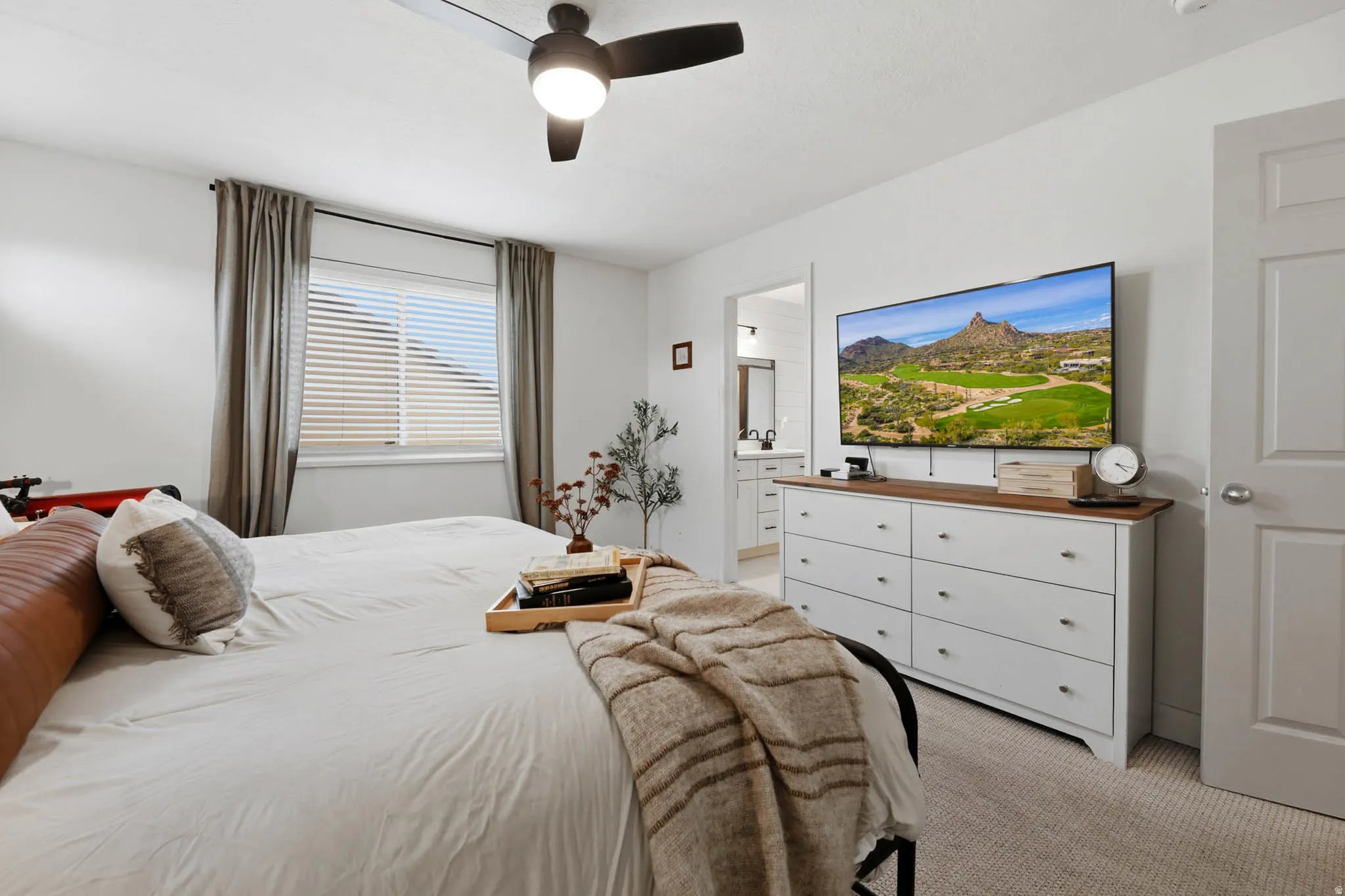 Bedroom featuring light colored carpet, a ceiling fan, and ensuite bath