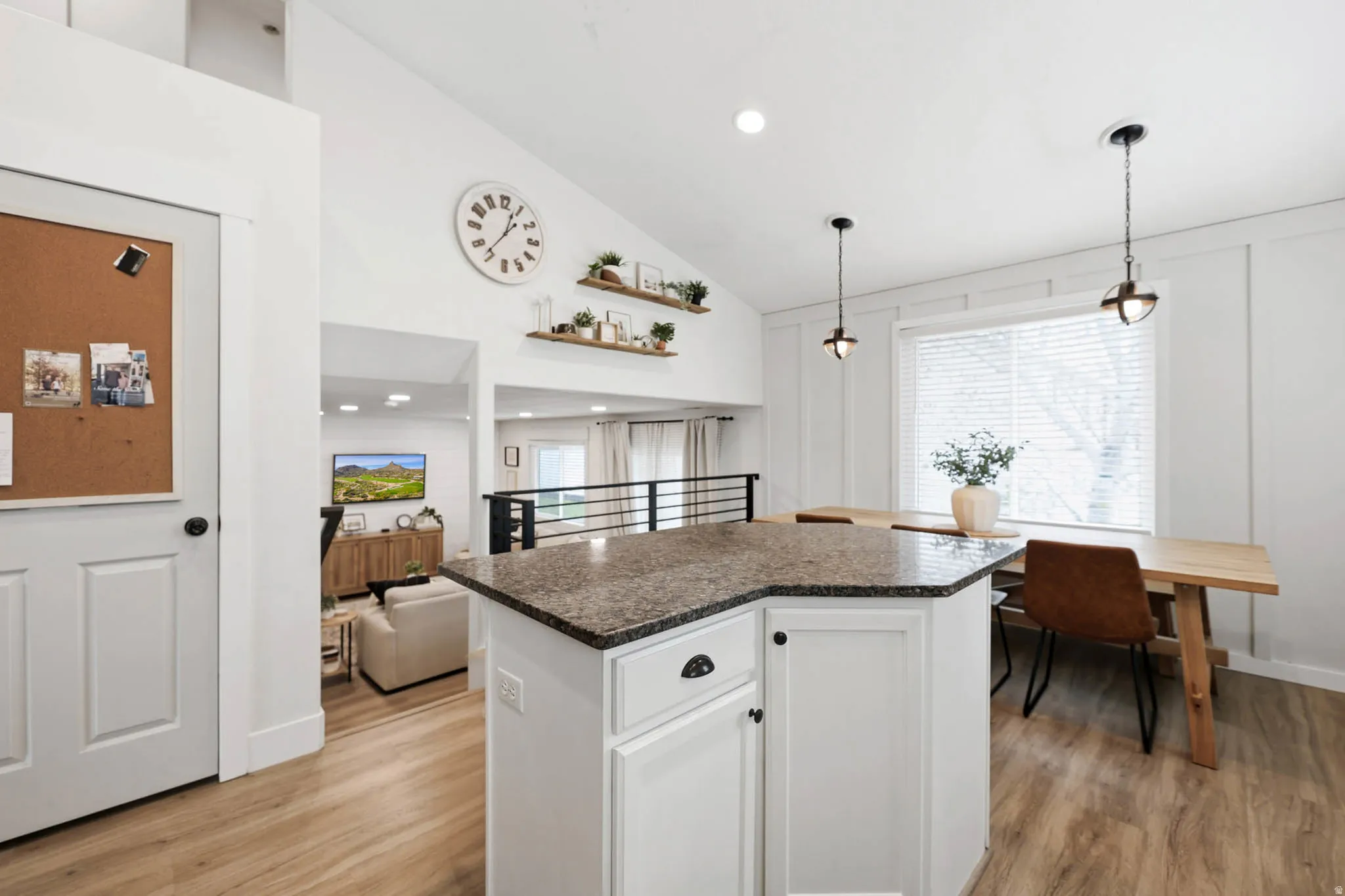 Kitchen featuring white cabinetry, a center island, decorative light fixtures, lofted ceiling, and light wood-type flooring
