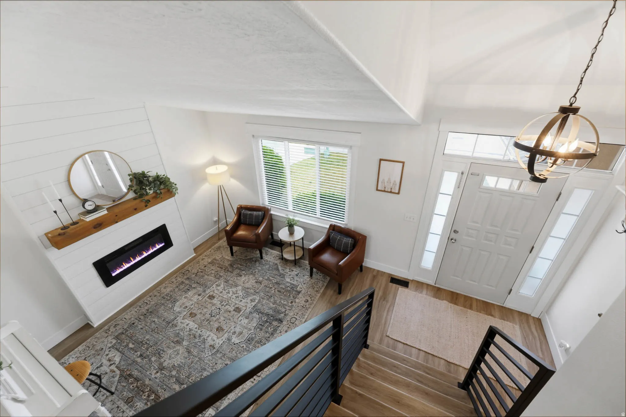Entrance foyer with dark wood-type flooring, a glass covered fireplace, and suspended lighting