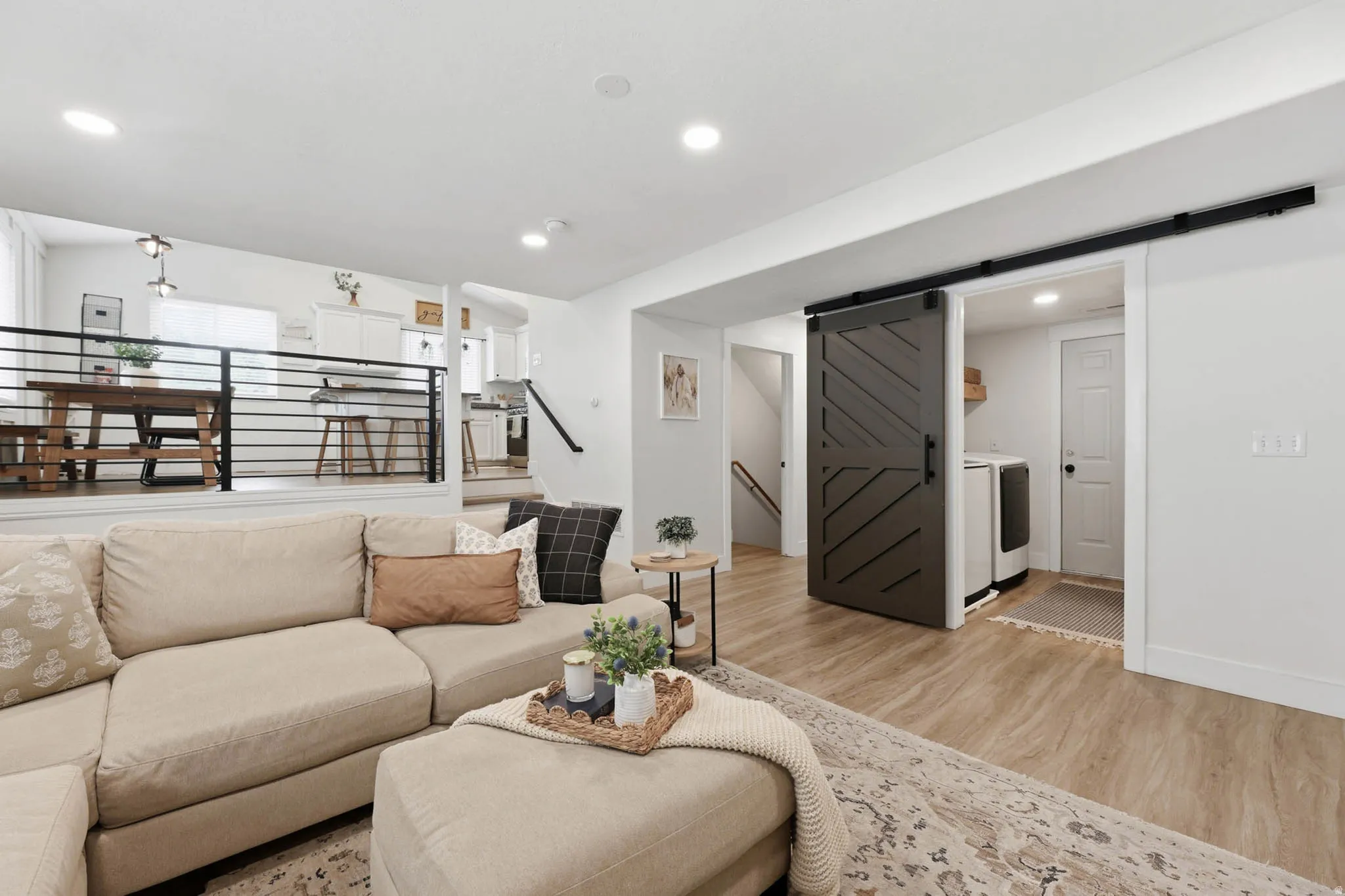 Living room featuring a barn door, light wood-style flooring, recessed lighting, and independent washer and dryer