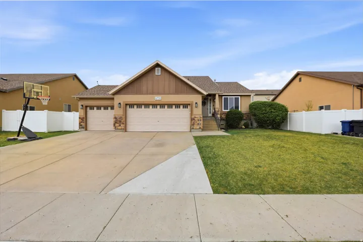 View of front of property with an attached garage, concrete driveway, stone siding, and stucco siding