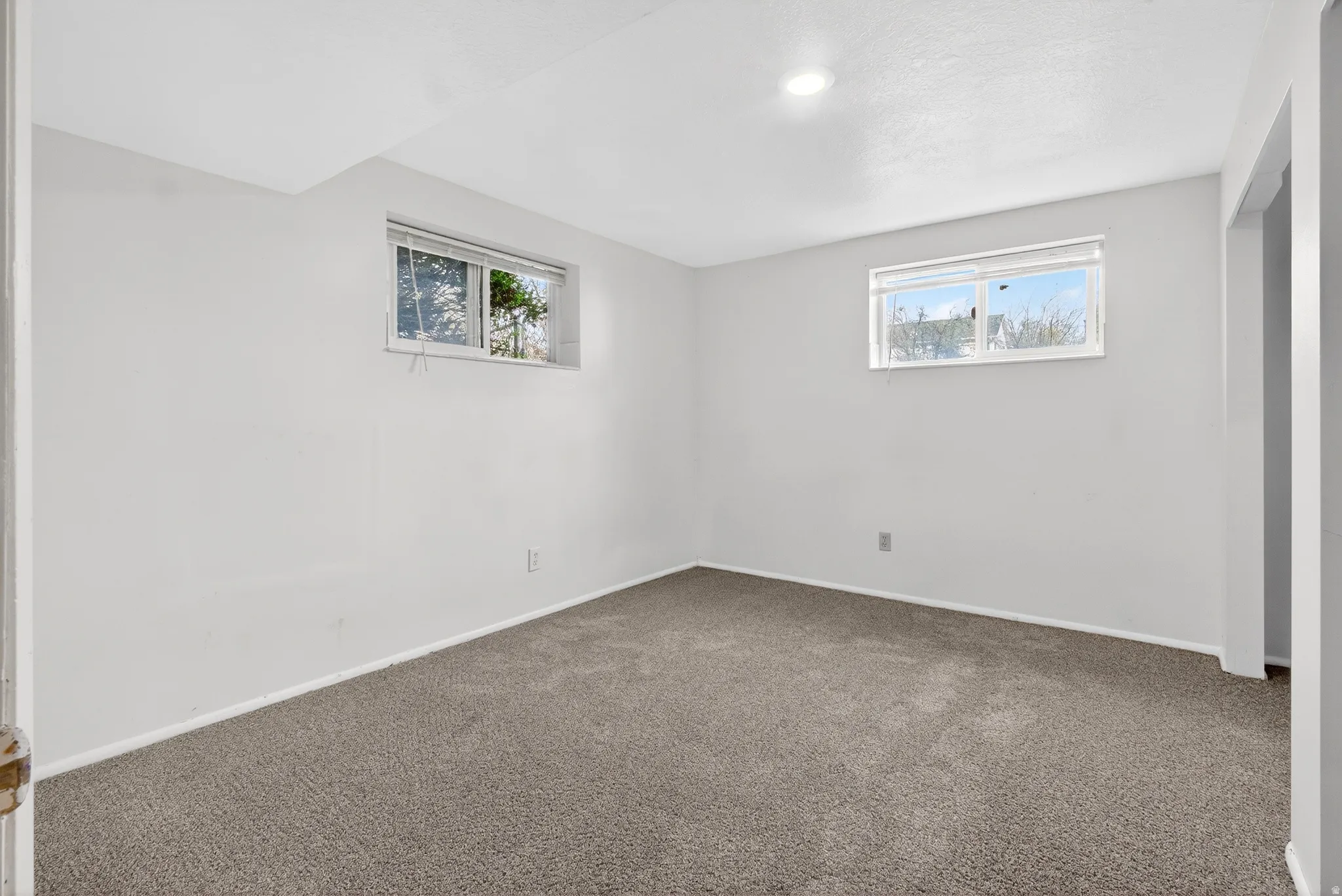 Unfurnished bedroom with dark colored carpet and multiple windows