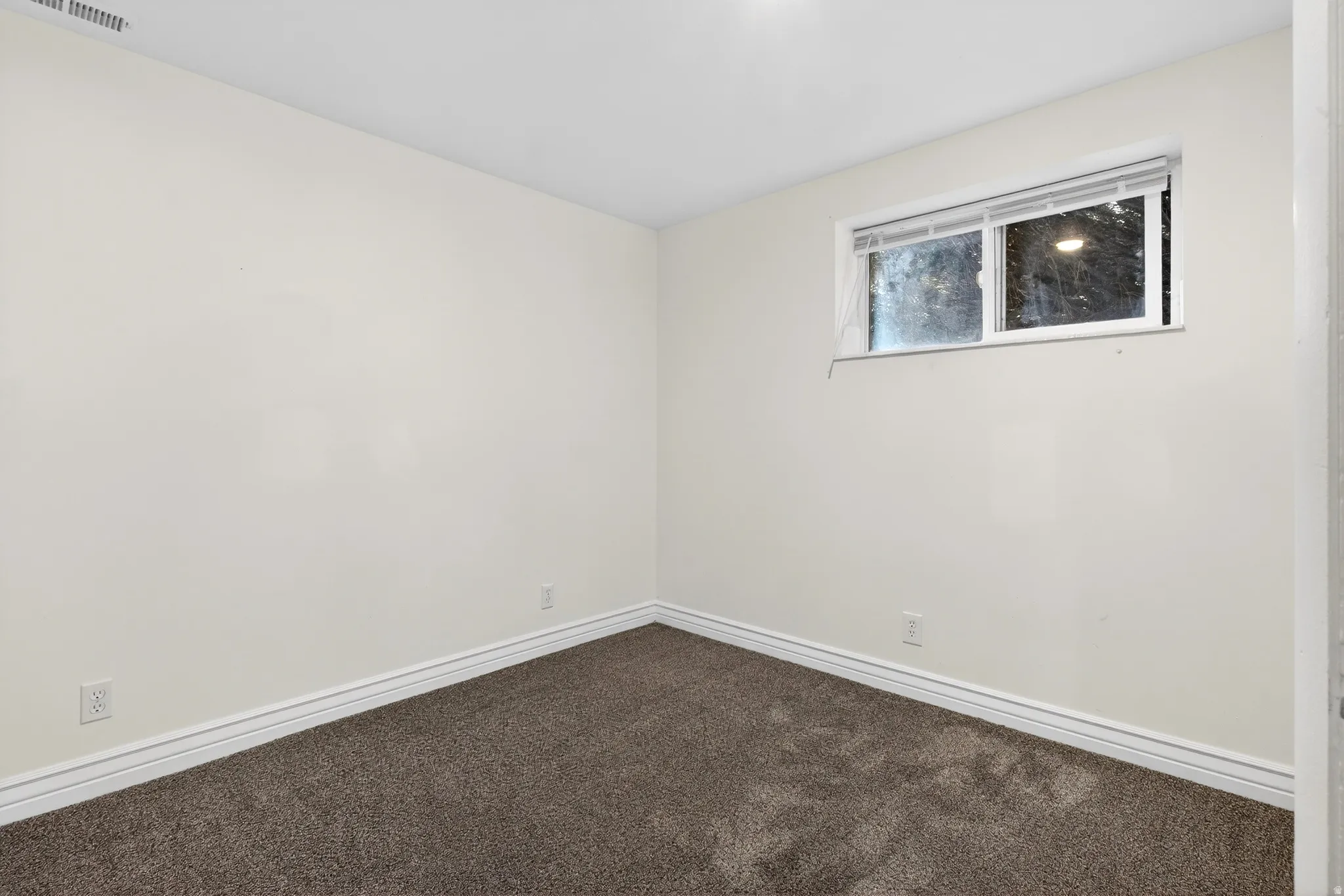 Spare room featuring dark colored carpet and baseboards