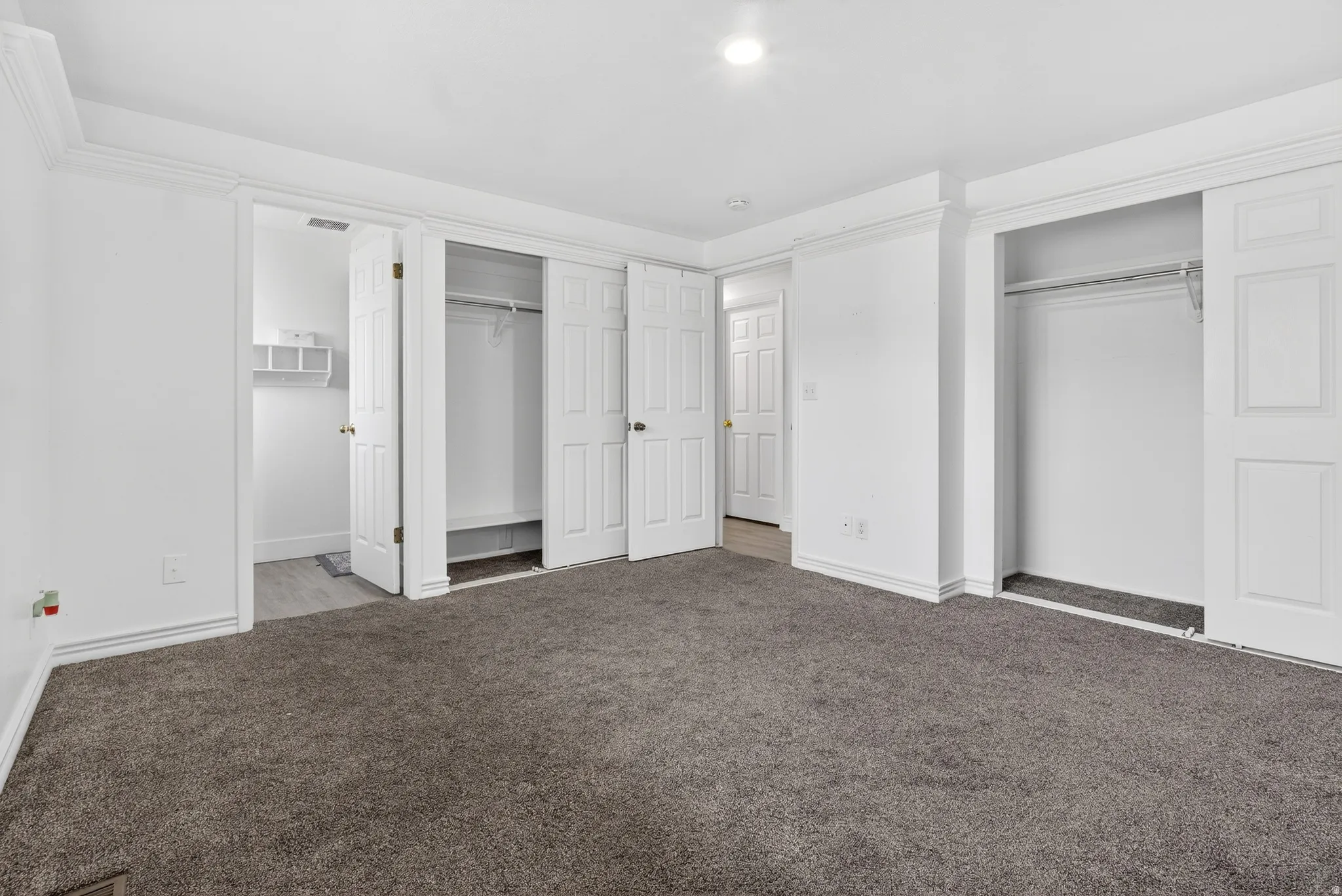 Unfurnished bedroom featuring two closets, carpet flooring, and ensuite bath