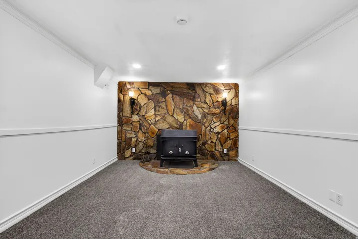 Detailed view of crown molding, carpet, and a wood stove