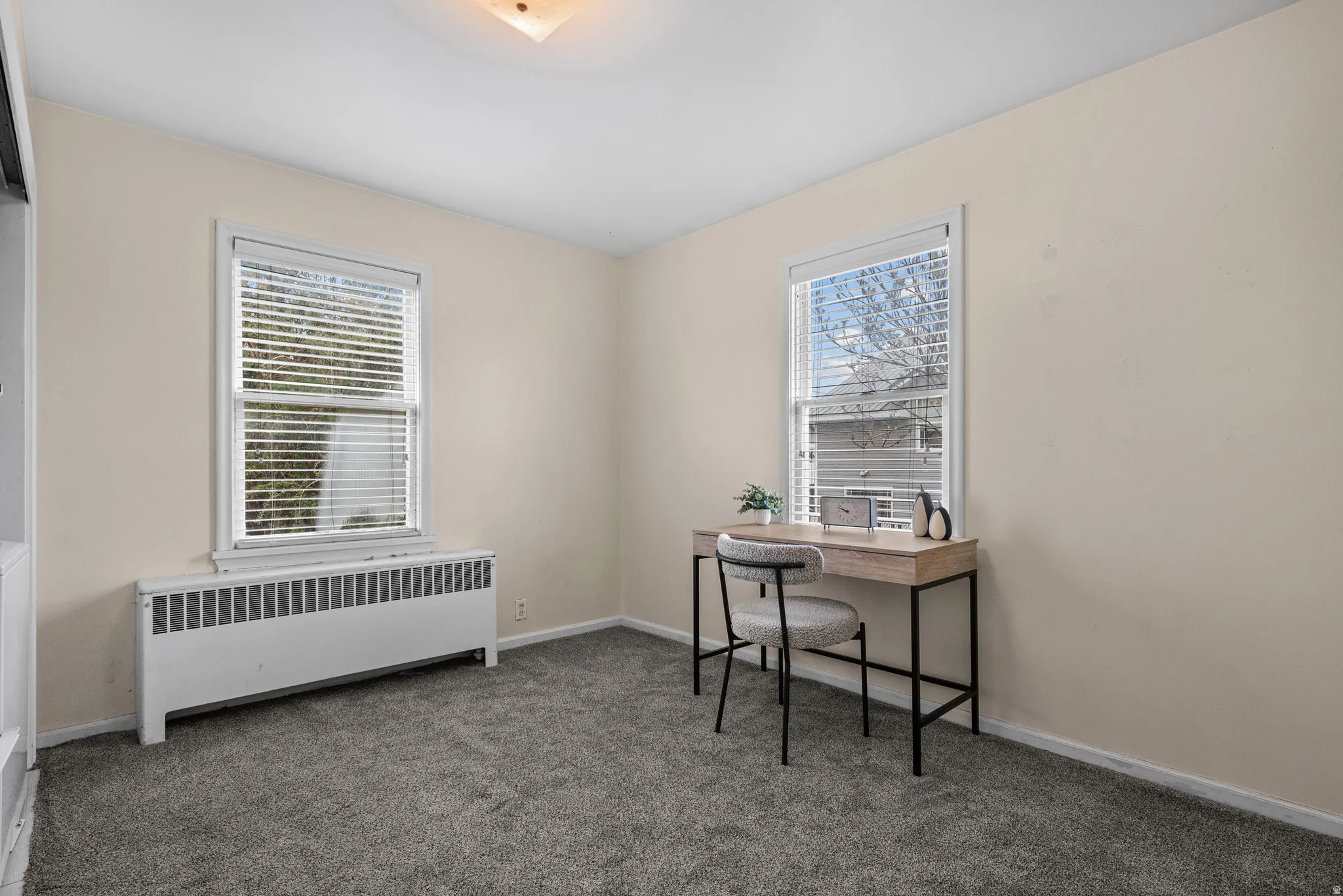 Home office with radiator and dark carpet