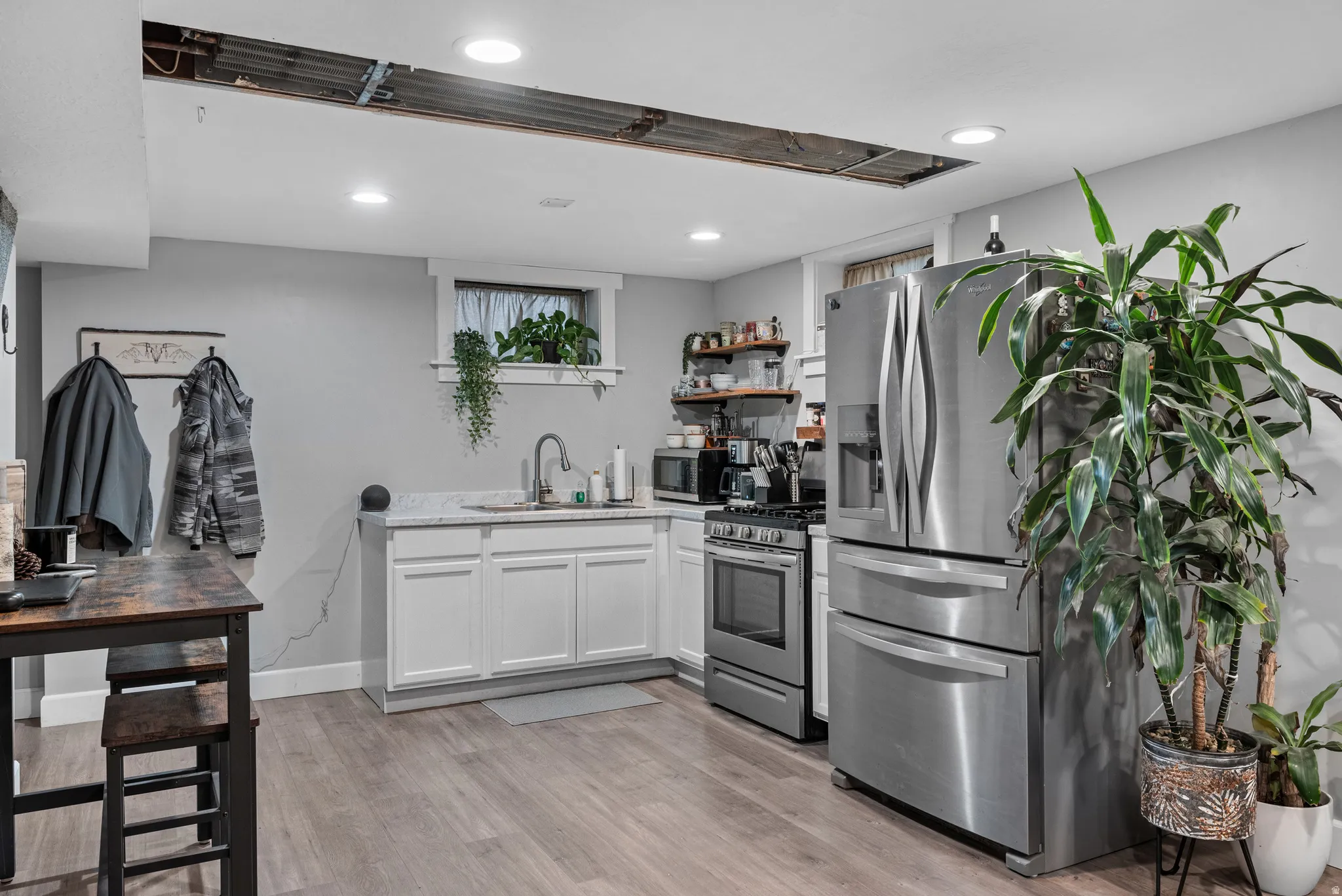 Kitchen with white cabinets, open shelves, stainless steel appliances, light wood finished floors, and recessed lighting