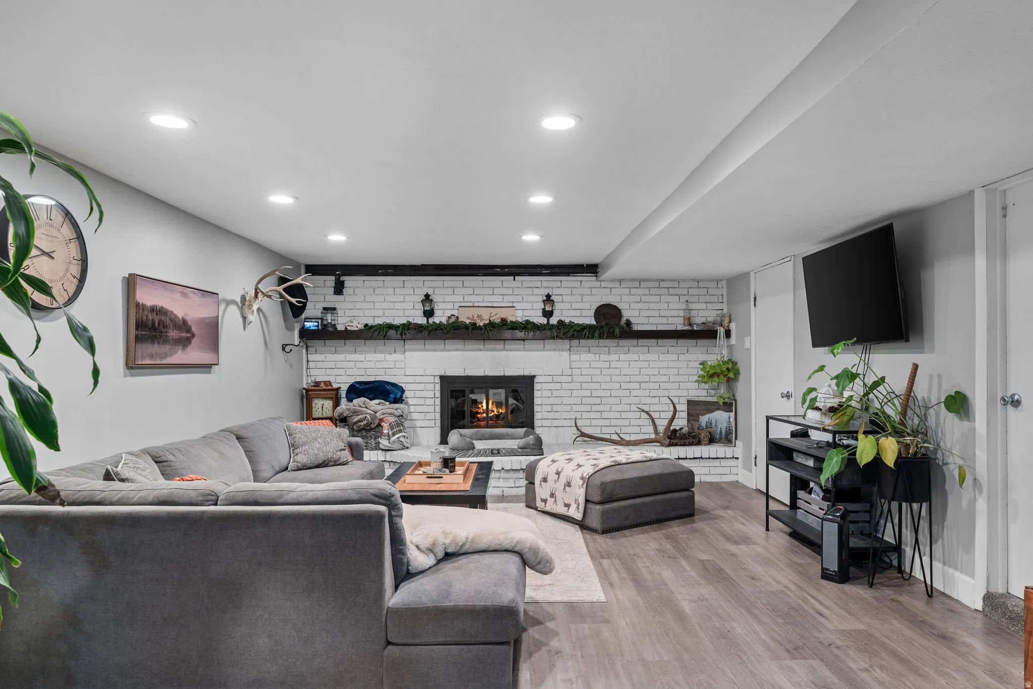 Living room featuring light wood-style flooring, recessed lighting, a fireplace, brick wall, and an accent wall