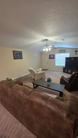 Carpeted living room featuring baseboards and a ceiling fan