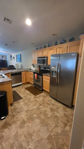 Kitchen with stone finish floors, stainless steel appliances, light wood finish cabinets, and a peninsula