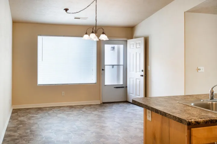 Kitchen featuring dark countertops, suspended lighting, and stone finish floors