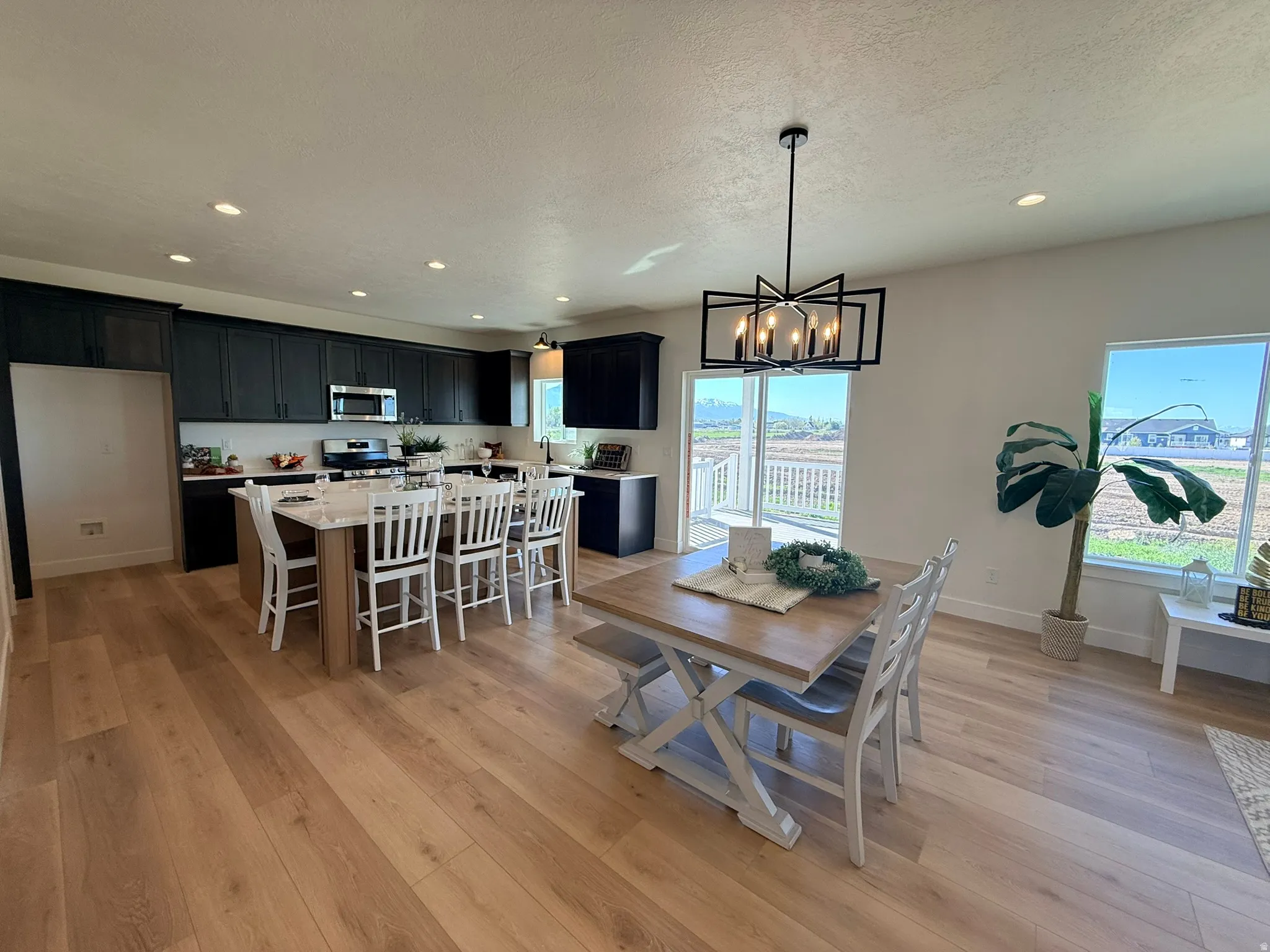 Dining space with light wood-style flooring, hanging lights, and a textured ceiling