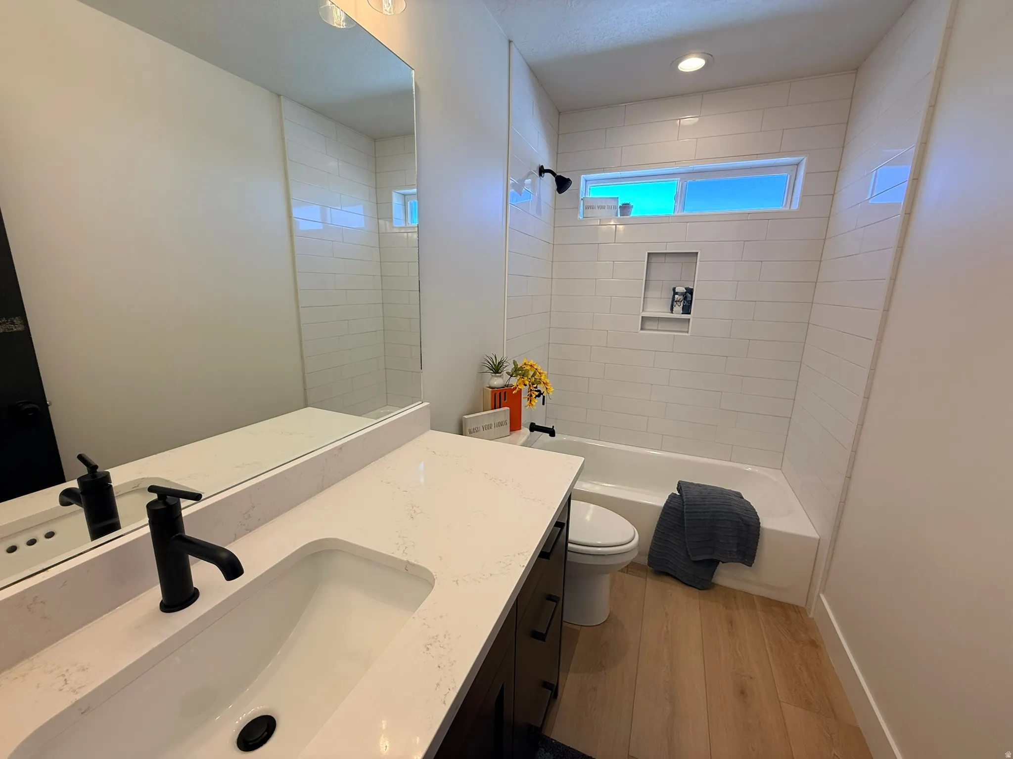 Bathroom featuring vanity, light wood-style flooring, washtub / shower combination, and recessed lighting
