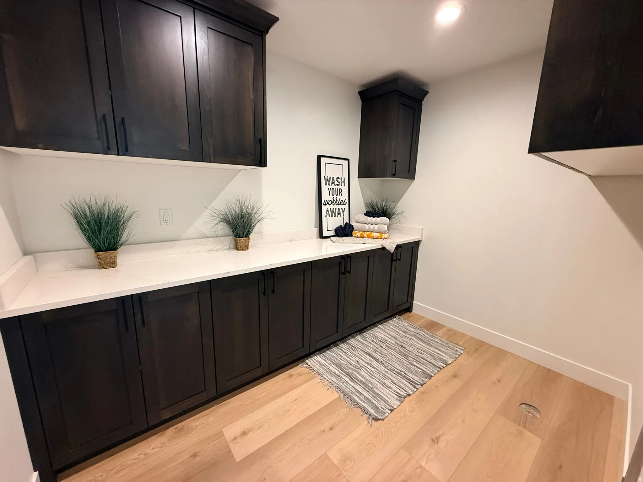 Laundry area featuring light wood-style flooring and baseboards