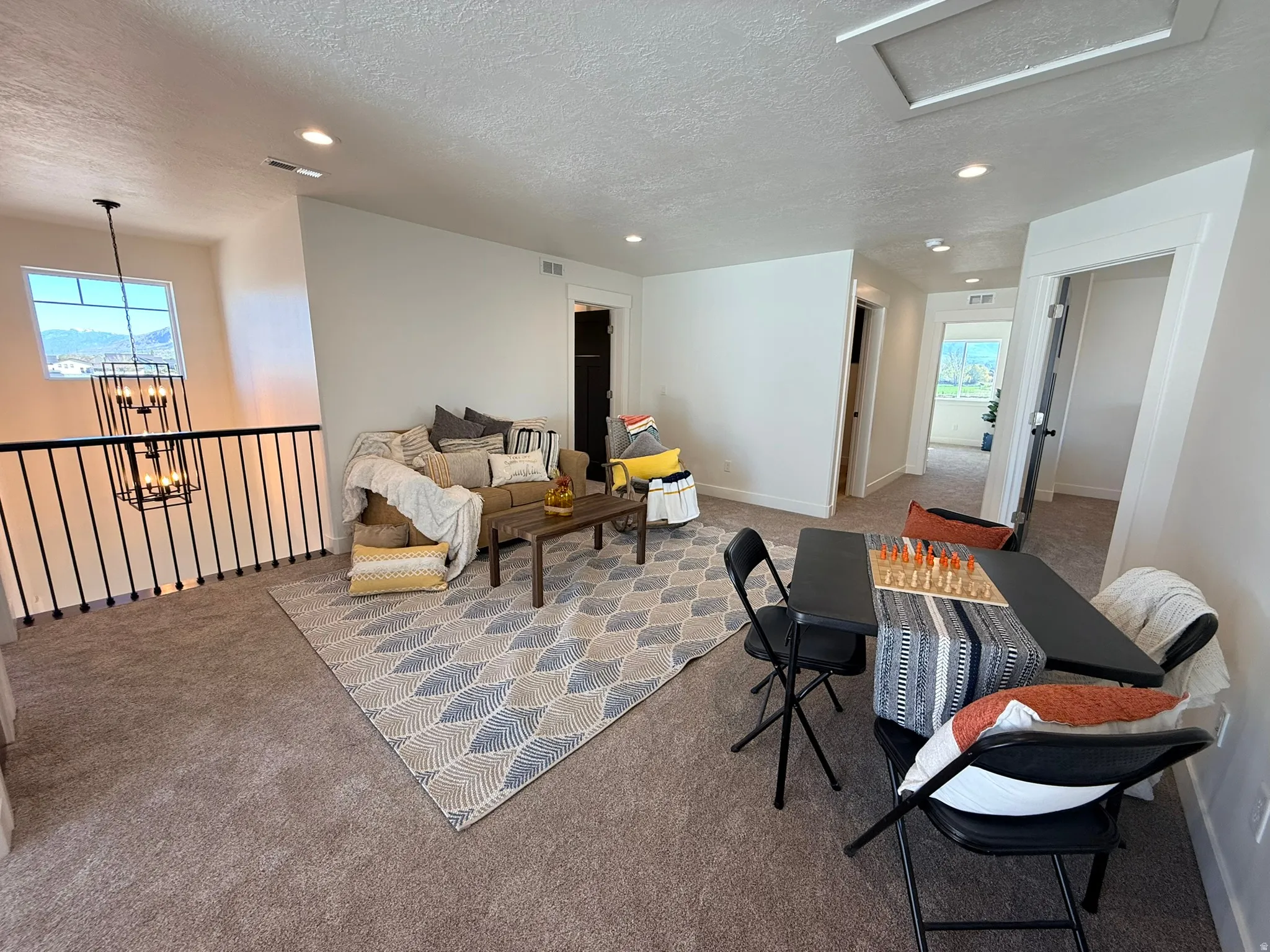 Living area featuring carpet, a textured ceiling, and hanging lights