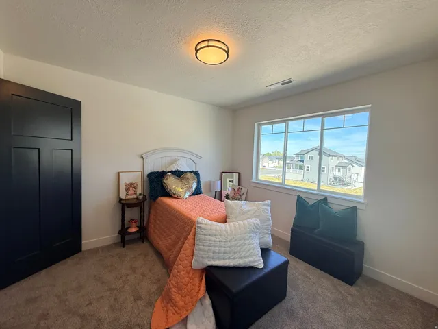 Carpeted bedroom featuring a textured ceiling and baseboards