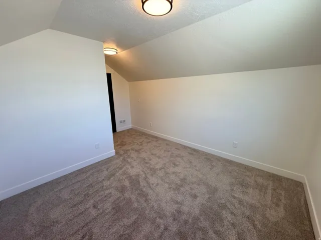 Additional living space with dark colored carpet and baseboards