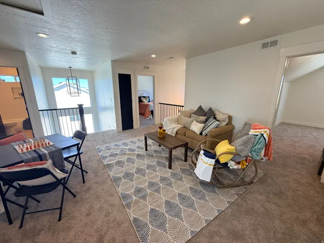 Carpeted living room with recessed lighting and a textured ceiling